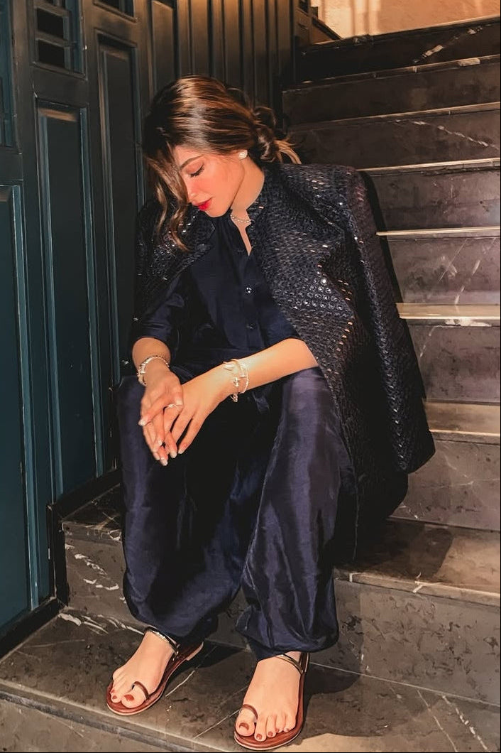 Woman sitting on a staircase in an urban setting with a blue wall and decorative elements.