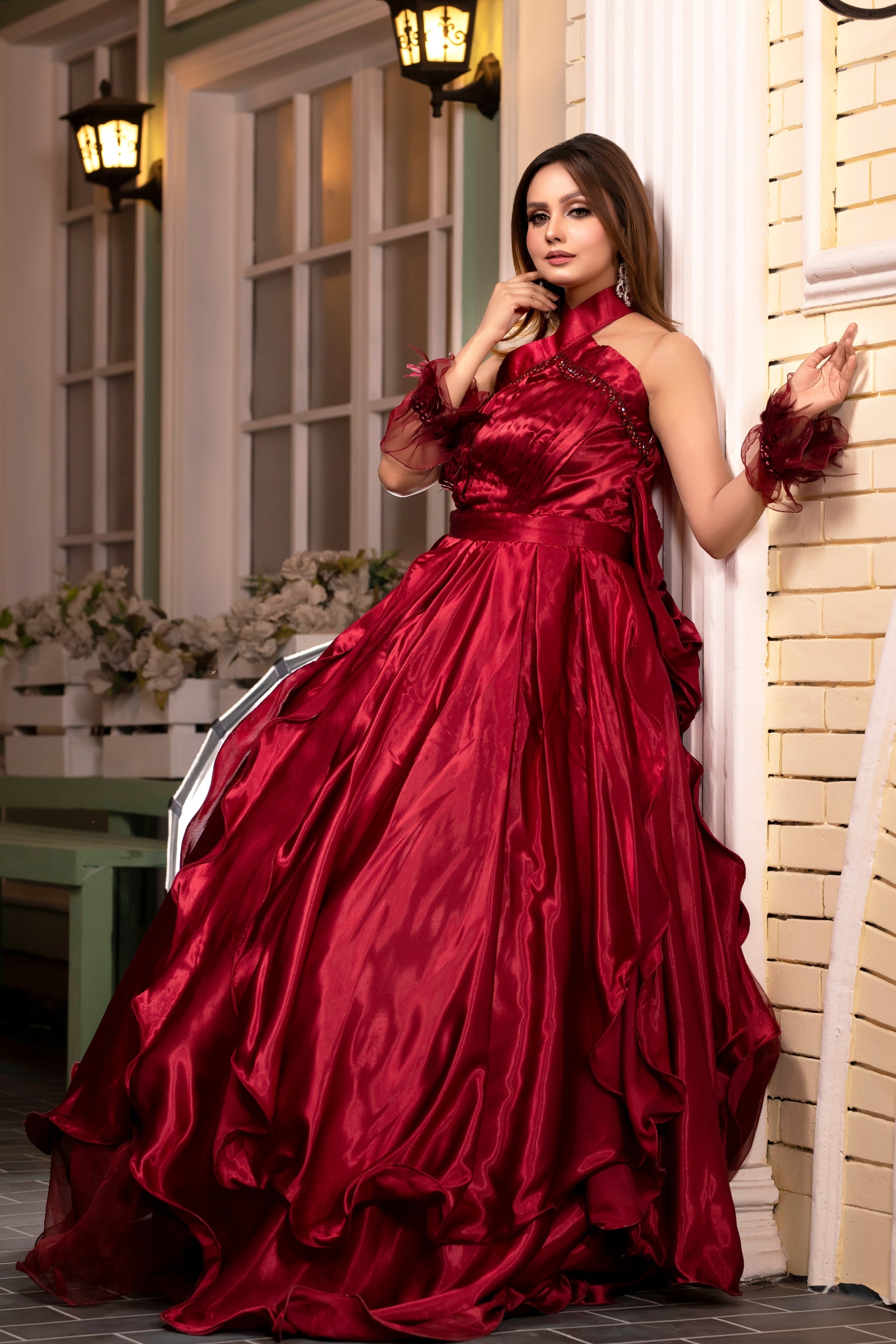Woman in a red evening gown standing against a decorative wall.