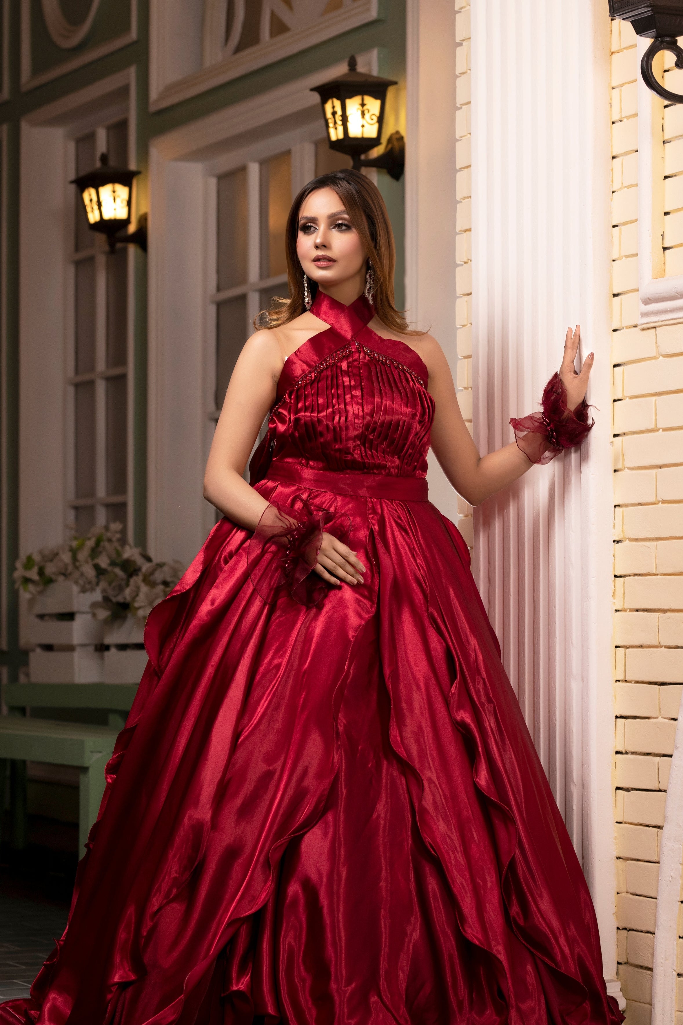 Woman in a red evening gown standing against a decorative wall.