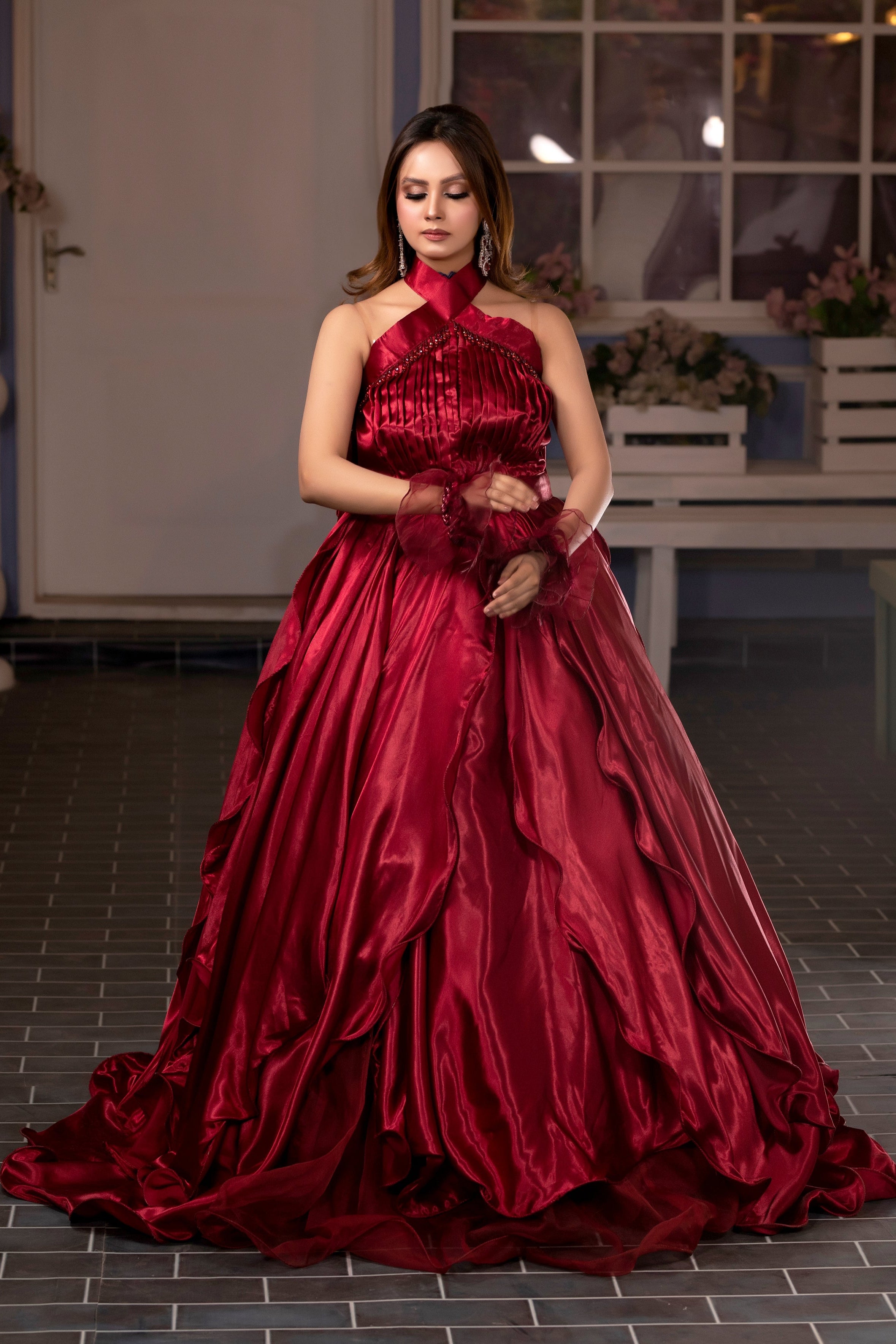 Woman in a red gown standing in an indoor setting with decorative elements.