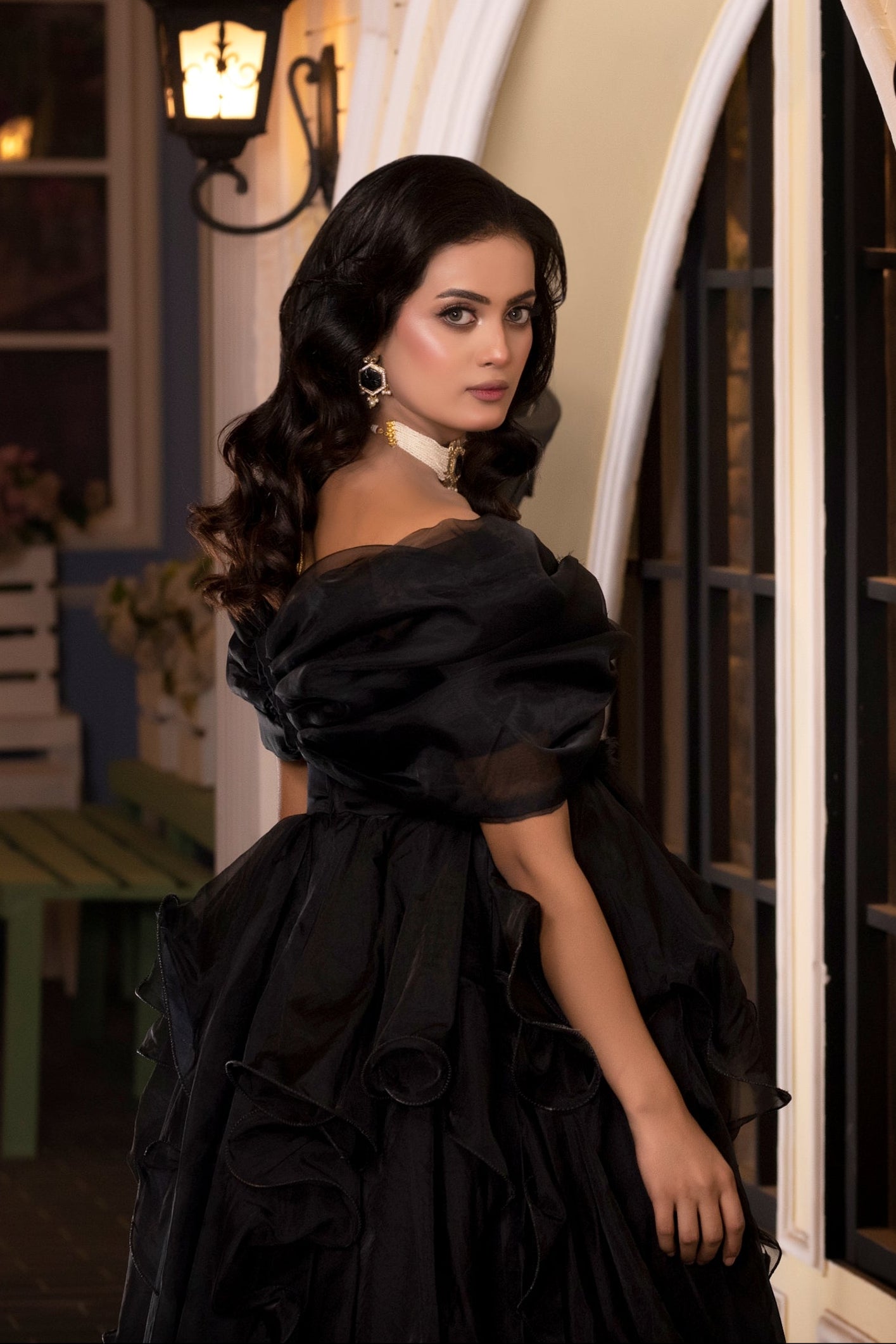 Woman in a black dress standing in front of a building with decorative lights.