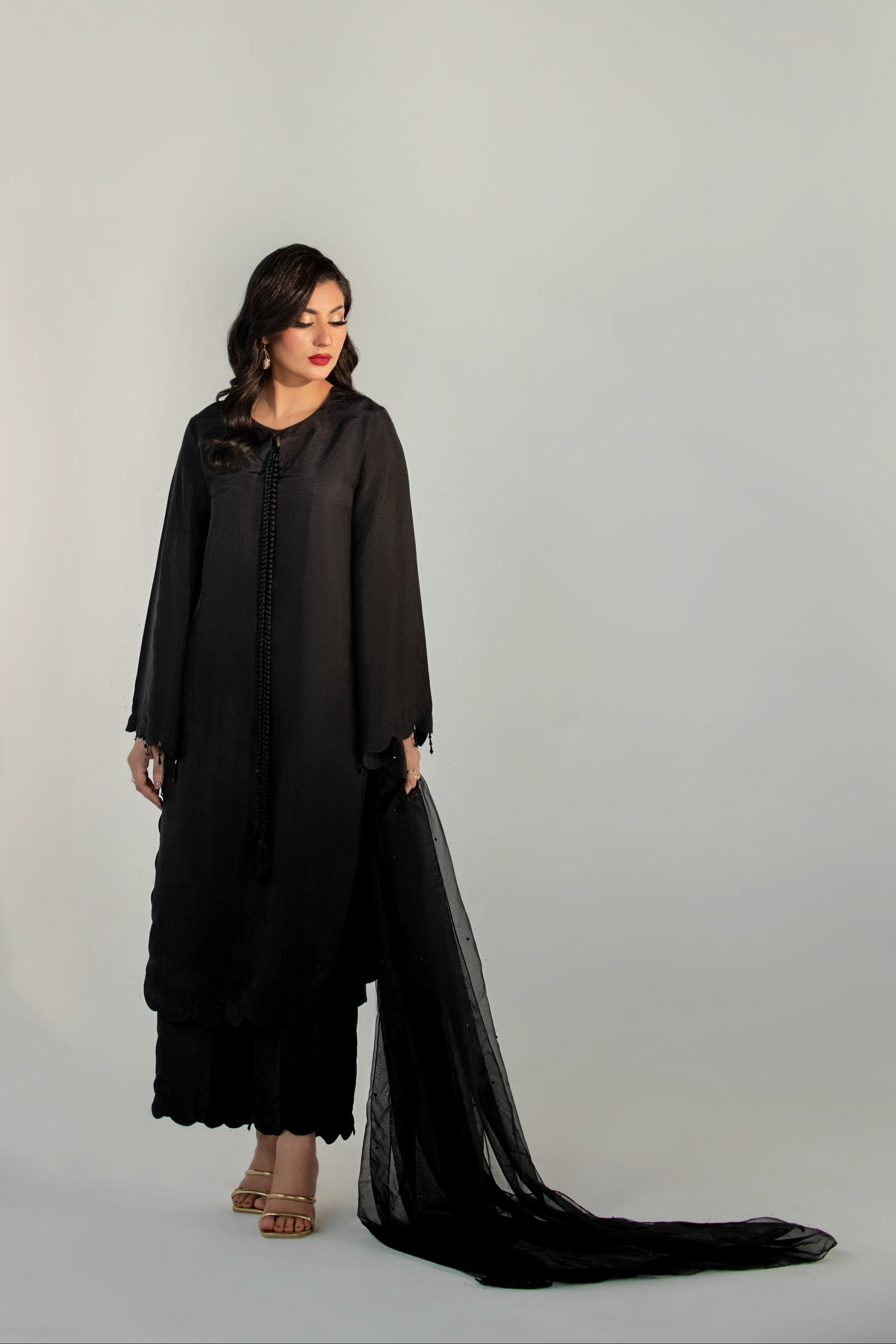 Woman wearing a black outfit with a flowing fabric on a white background