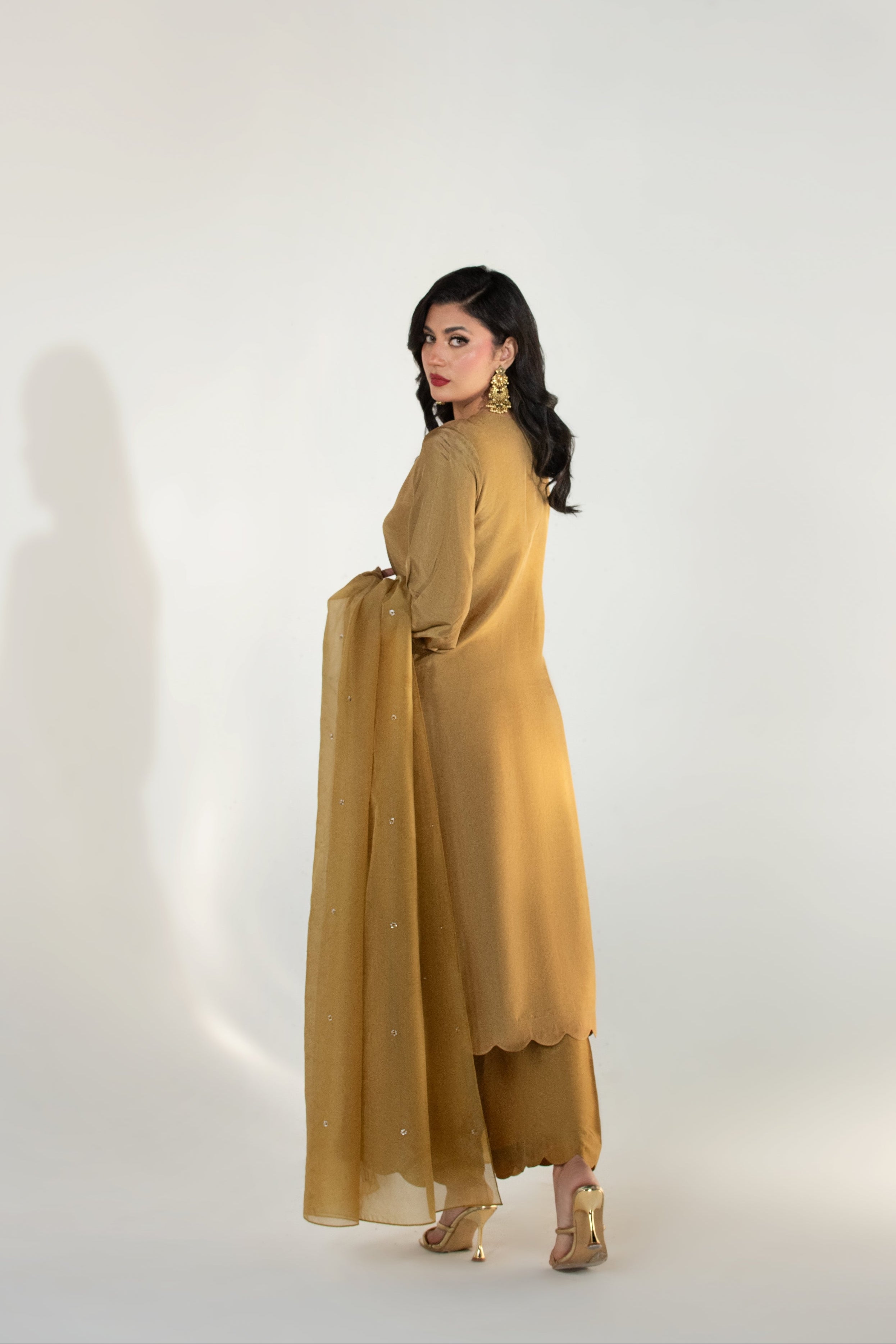 Woman wearing a mustard yellow outfit against a white background