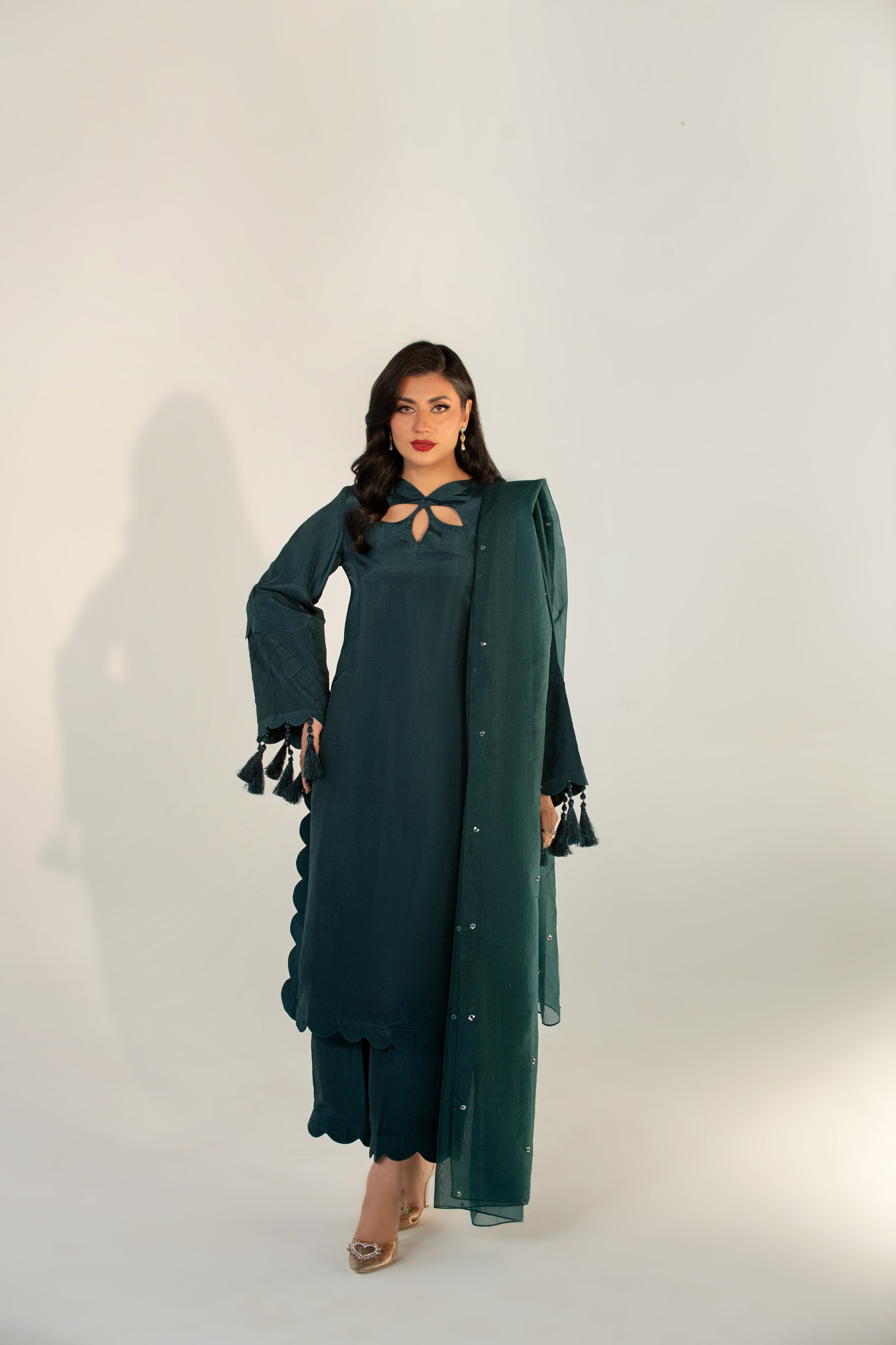 Woman wearing a green dress with a matching shawl against a white background