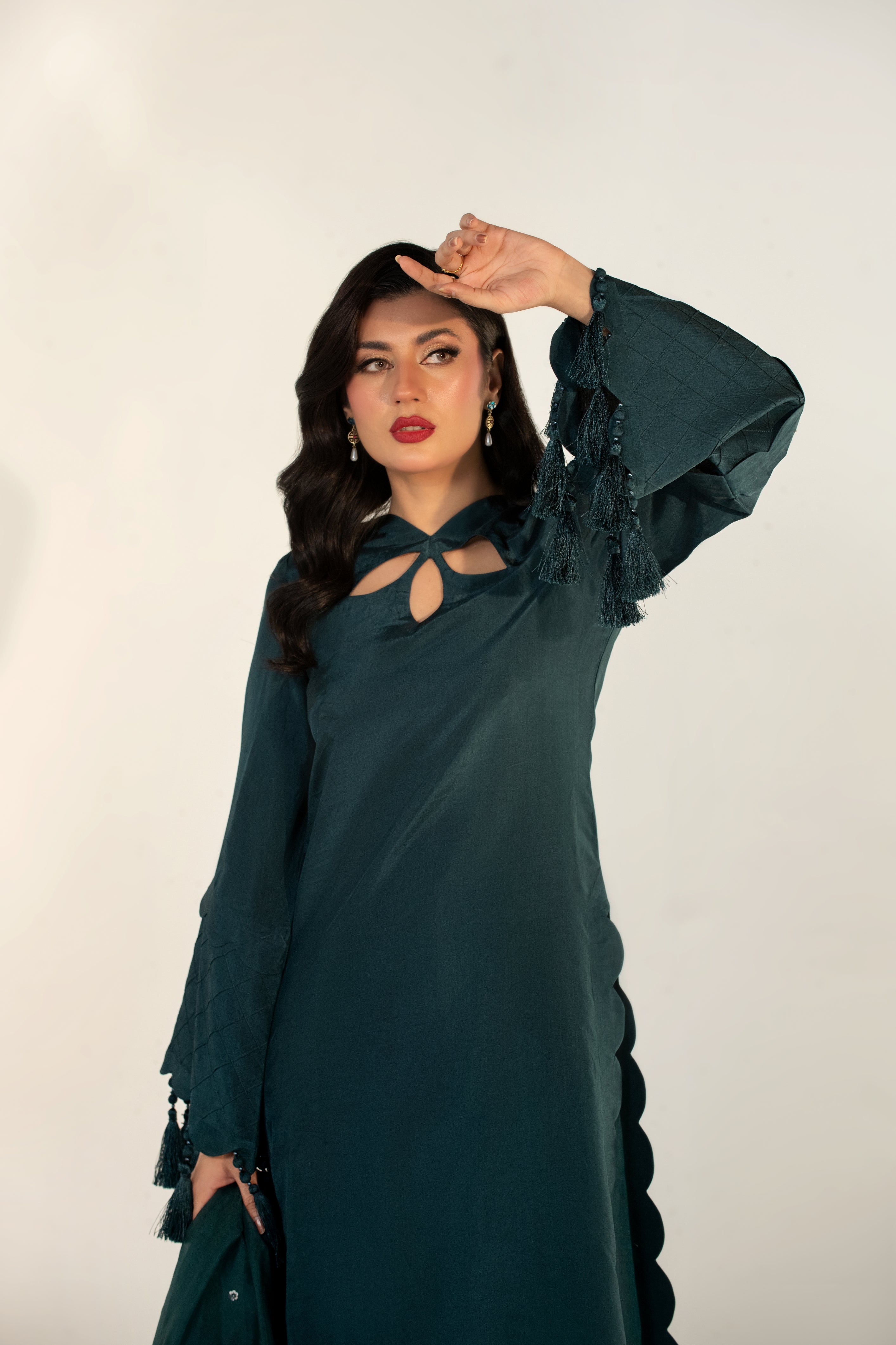 Woman wearing a dark green dress with long sleeves against a white background