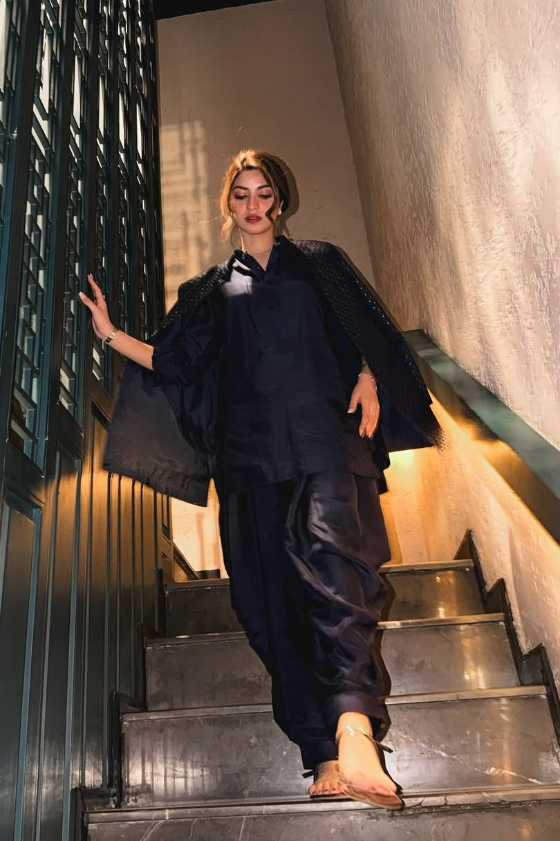 Person in a black outfit walking up a staircase in an indoor setting.