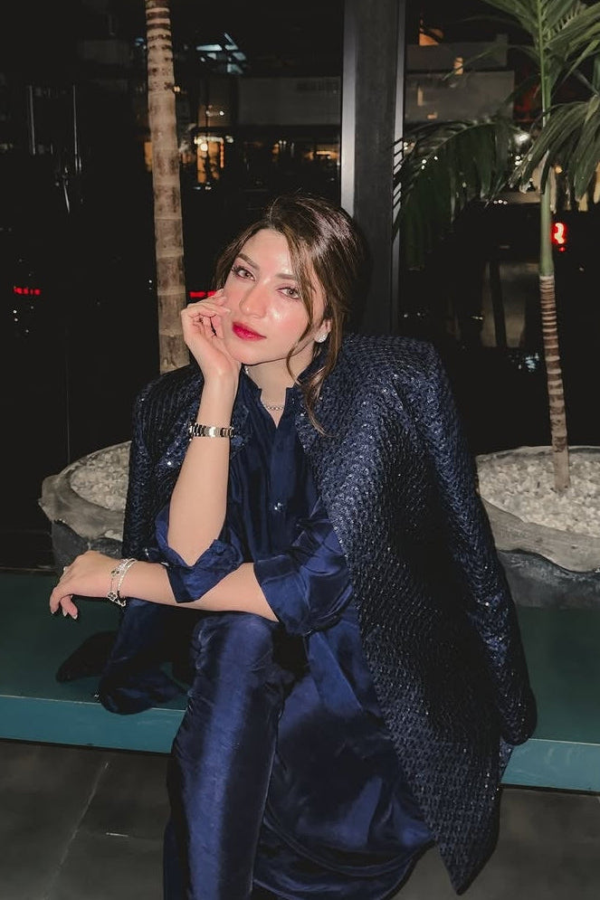 Woman in a blue dress sitting on a bench with palm trees in the background