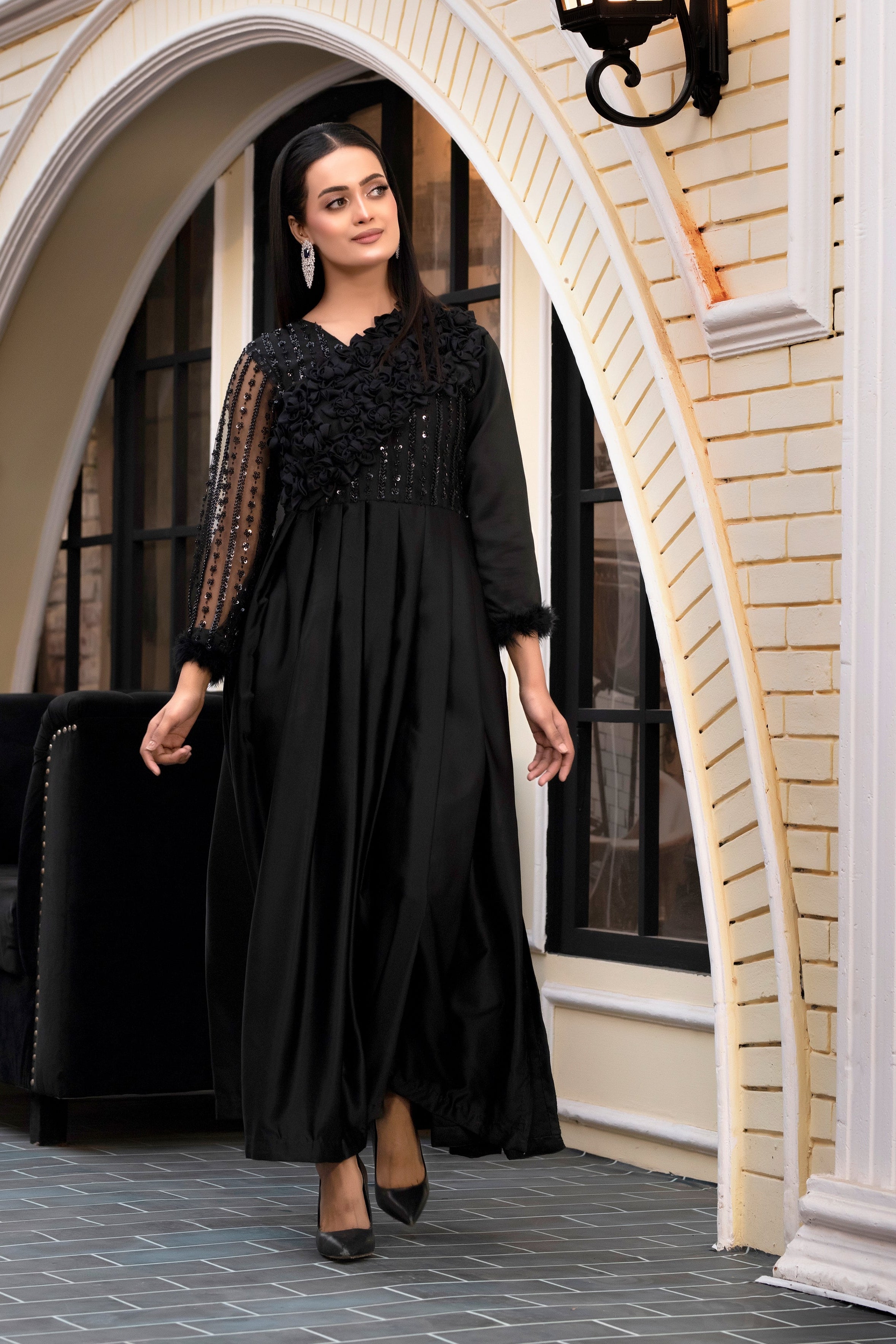 Woman in a black dress standing in an archway with decorative elements.