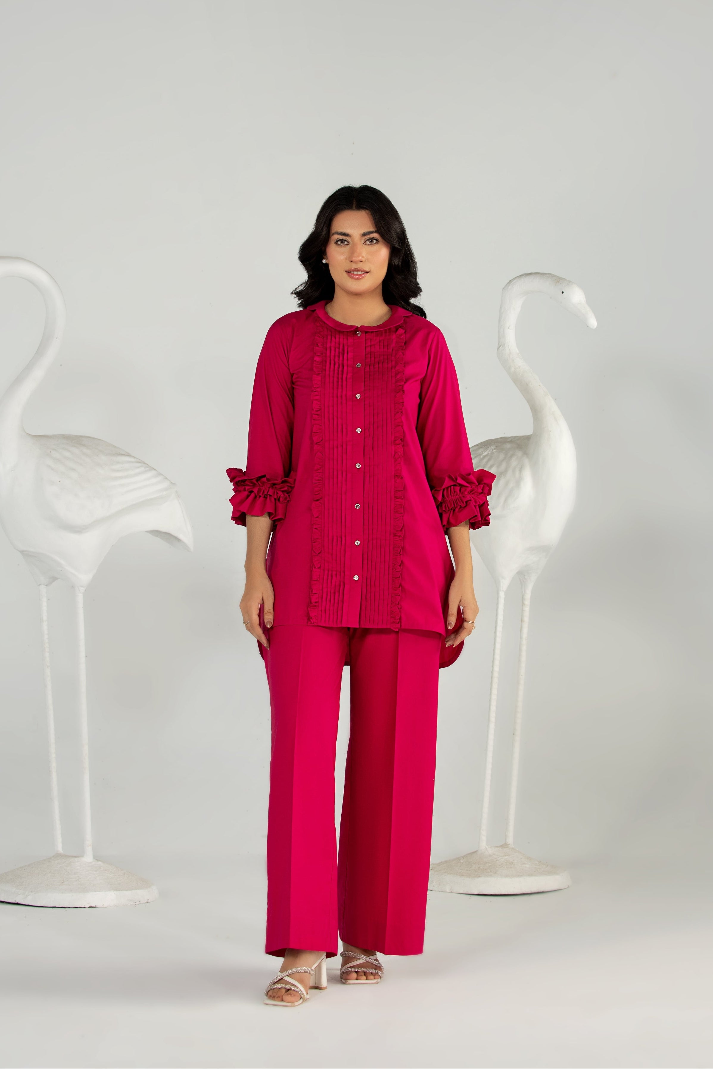 Woman wearing a red outfit standing between two white chairs on a gray background