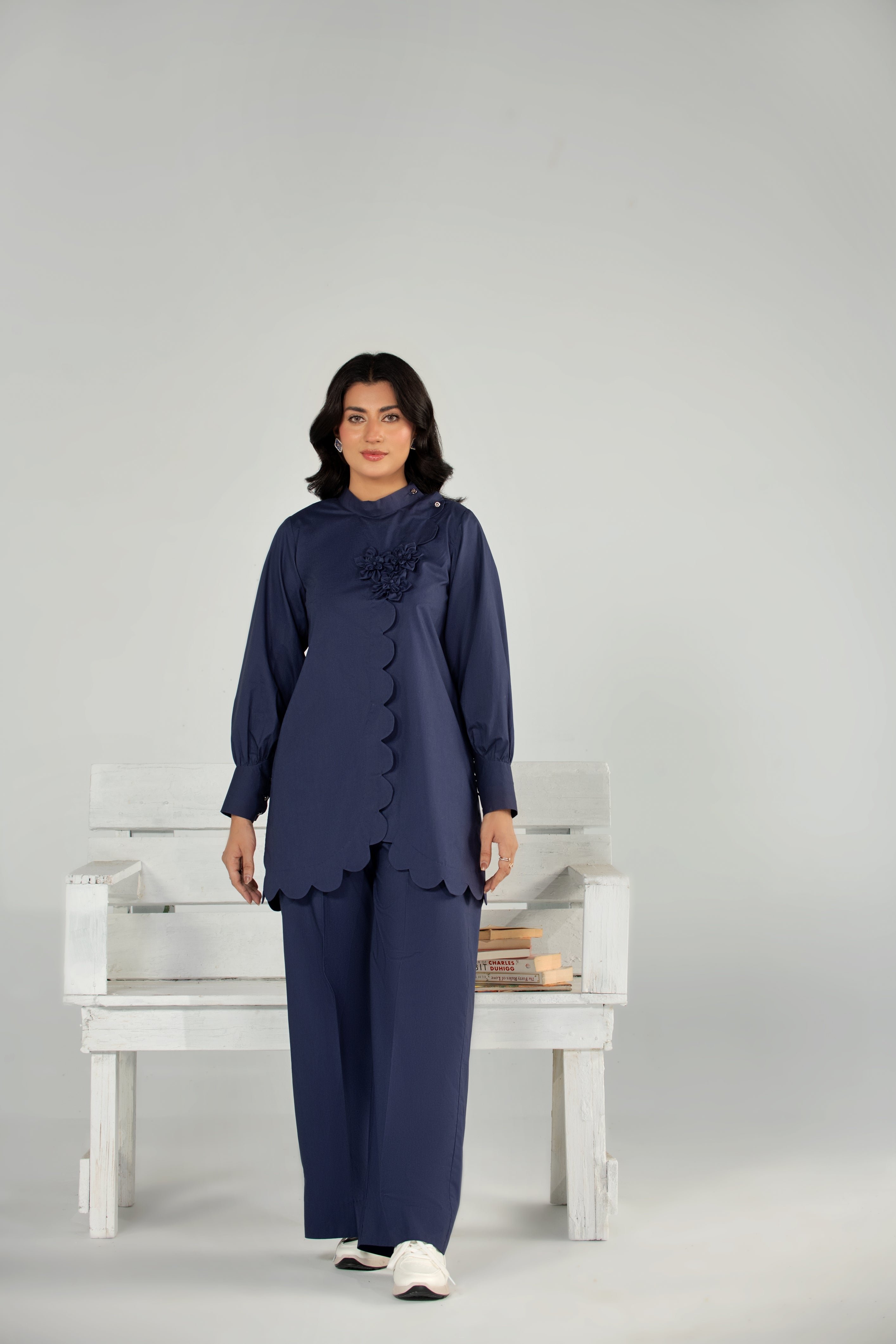 Woman wearing a navy blue outfit with a white background