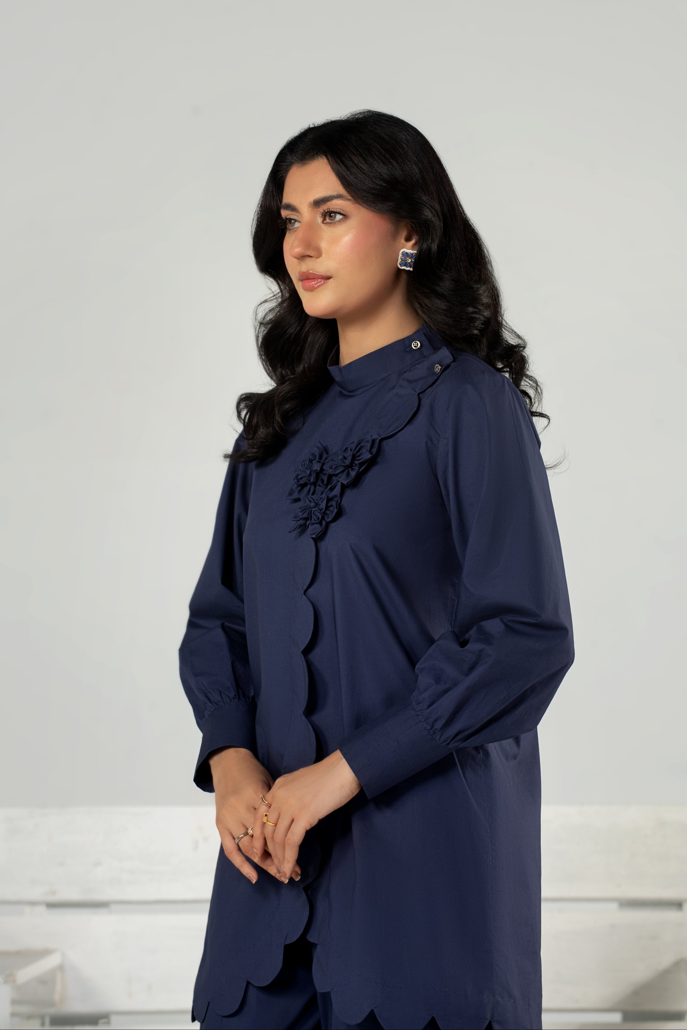 Woman wearing a navy blue dress with floral details against a white background