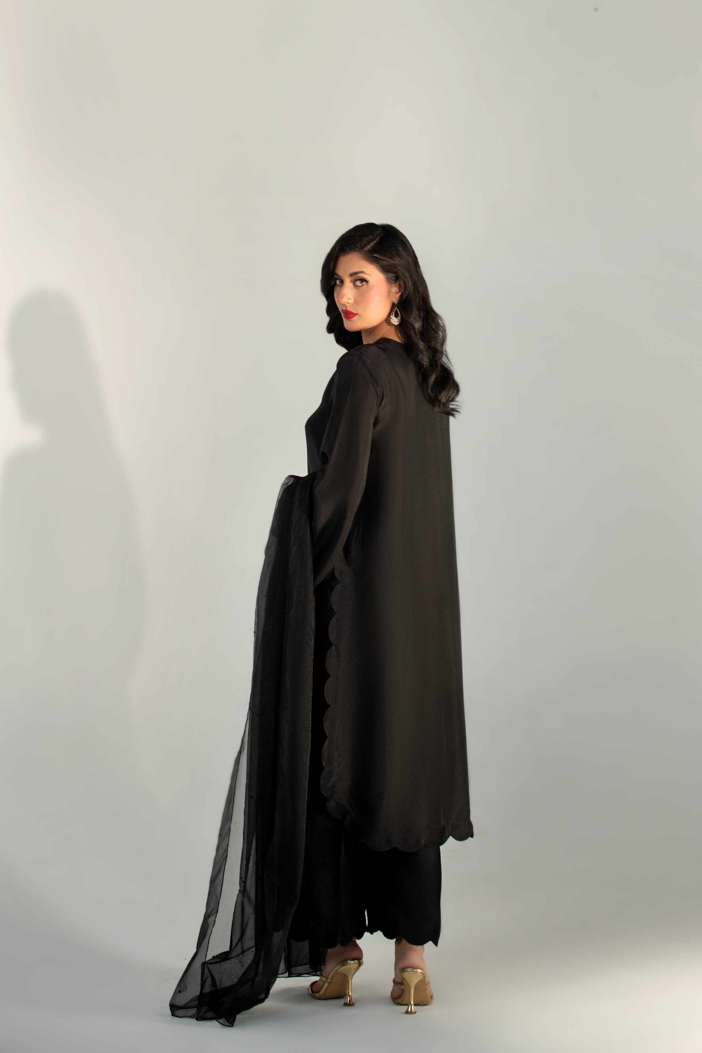 Woman wearing a black outfit with sheer sleeves against a white background