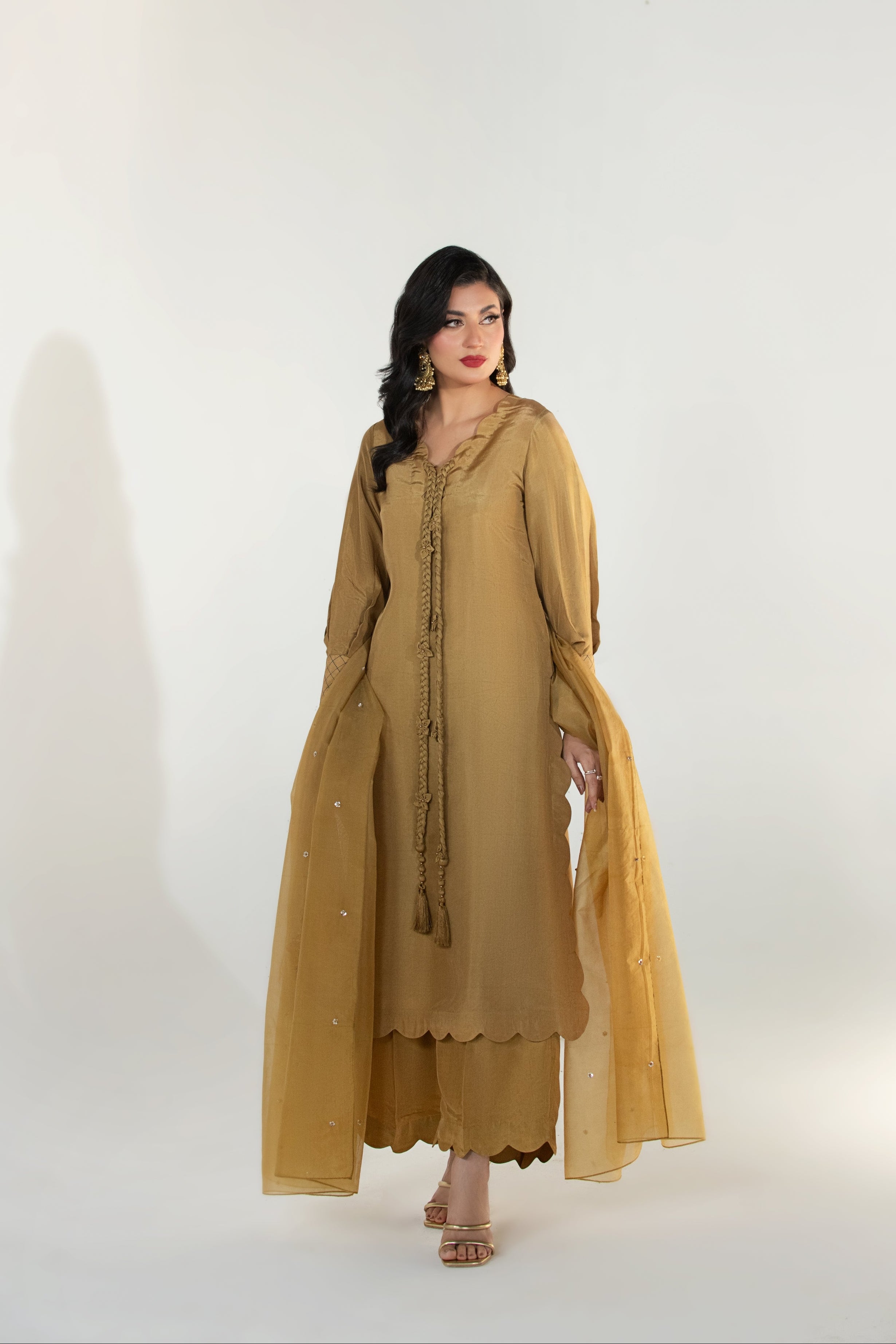 Woman wearing a mustard yellow traditional outfit on a white background