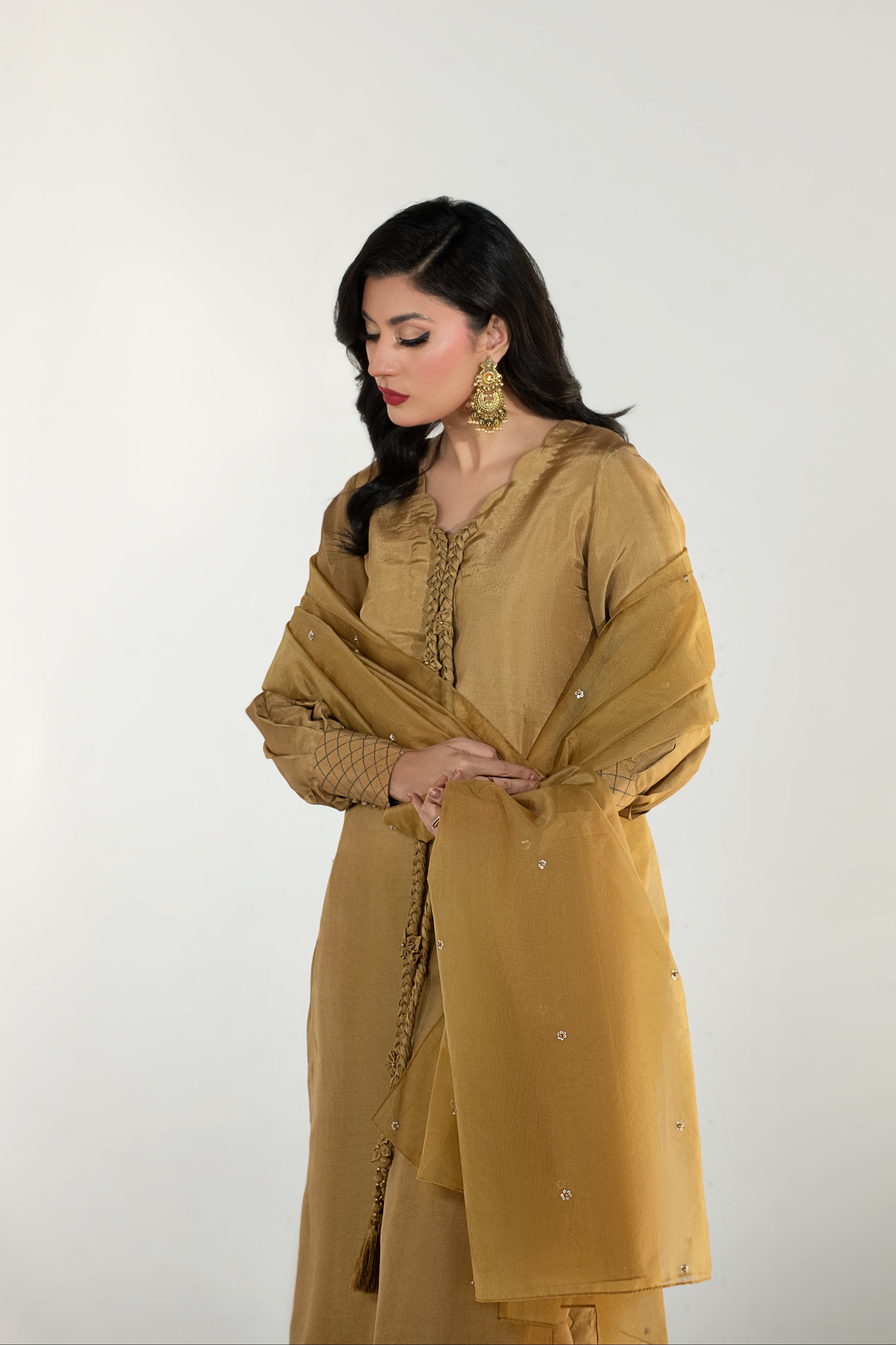 Woman wearing a mustard yellow traditional outfit with a plain background