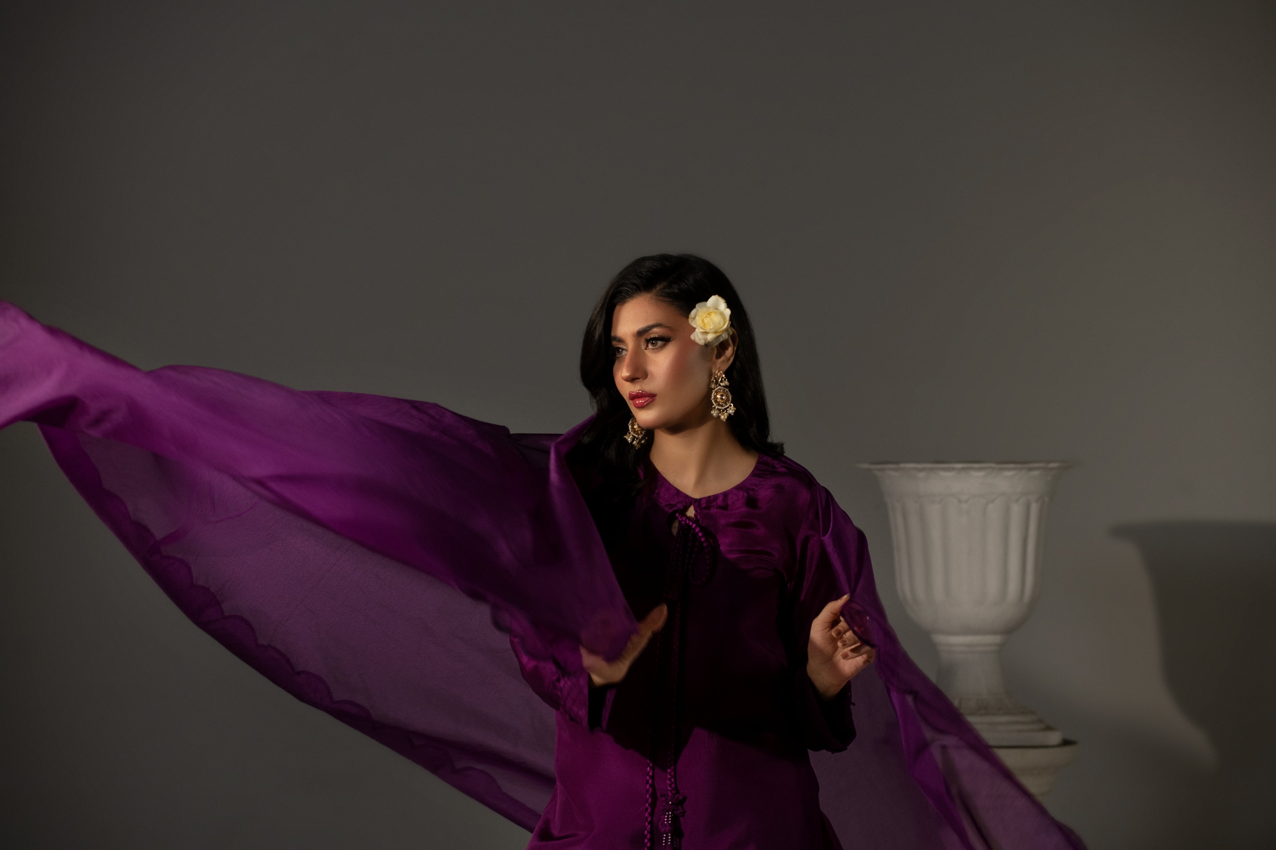 Woman in a purple dress with a white vase in the background